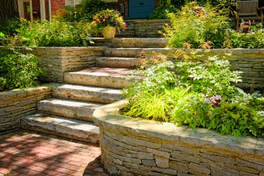 brick walkway that leads up to stone stairs and side retaining walls